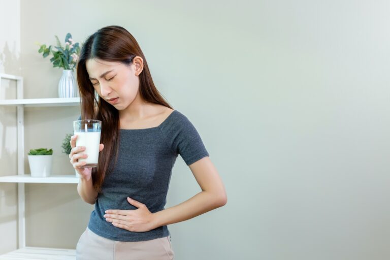 Asian female unhappy holding glass milk and stomach ache after drinking milk.